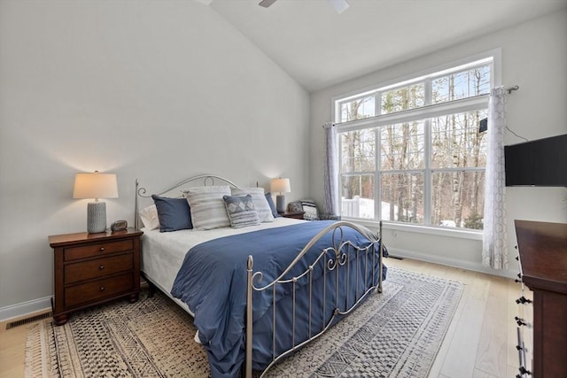 bedroom featuring a ceiling fan, baseboards, vaulted ceiling, and wood finished floors