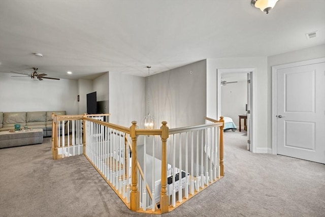 hallway featuring visible vents, carpet floors, an upstairs landing, and a notable chandelier