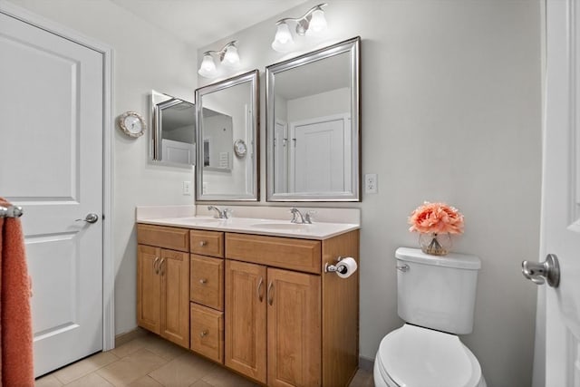 bathroom with double vanity, a sink, toilet, and tile patterned floors