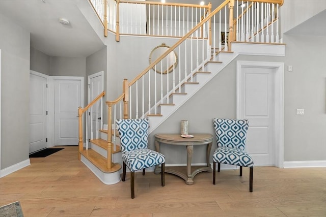 interior space with a towering ceiling, baseboards, and wood finished floors