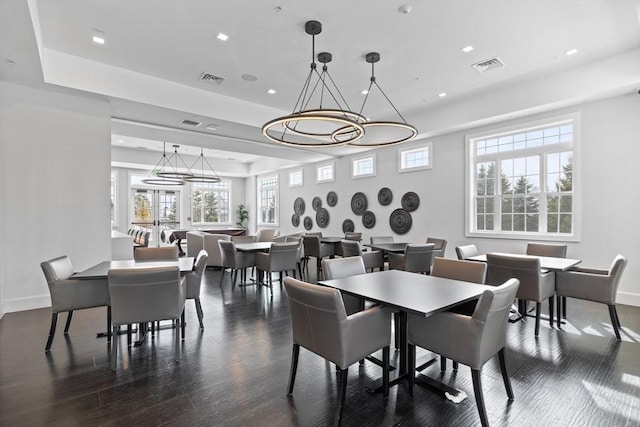 dining room featuring baseboards, visible vents, a tray ceiling, and dark wood-type flooring