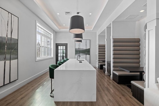 interior space featuring wood finished floors, a raised ceiling, and visible vents