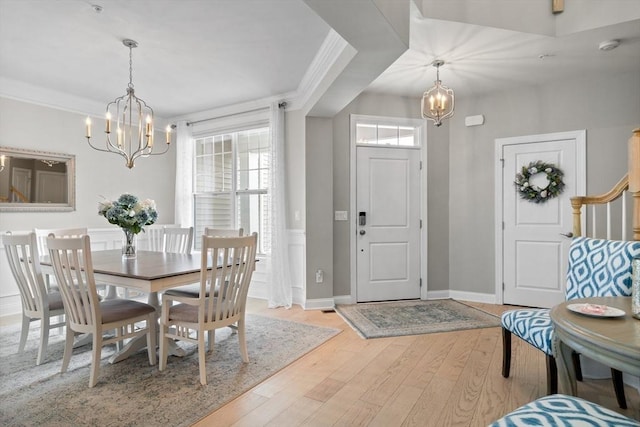 entryway featuring a chandelier, wainscoting, ornamental molding, and light wood-style flooring