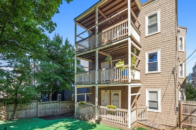 back of house featuring a porch, a balcony, and a lawn