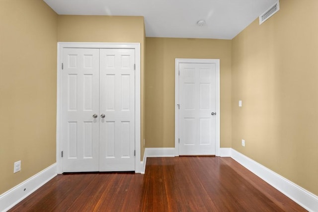 unfurnished bedroom with dark hardwood / wood-style flooring and a closet