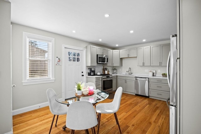 kitchen featuring gray cabinetry, sink, light hardwood / wood-style flooring, and appliances with stainless steel finishes