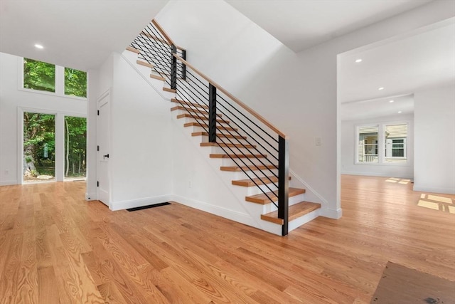 stairs with hardwood / wood-style flooring and a healthy amount of sunlight