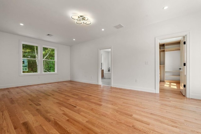 interior space featuring connected bathroom, a walk in closet, and light hardwood / wood-style floors