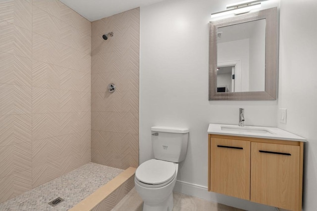 bathroom featuring tiled shower, vanity, and toilet