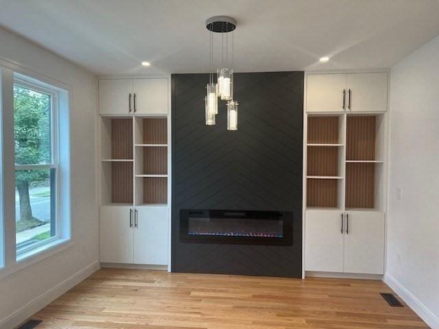 unfurnished living room featuring a notable chandelier and light hardwood / wood-style floors