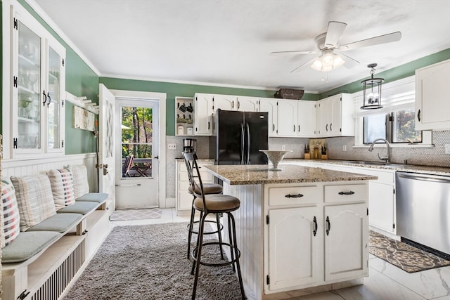 kitchen with sink, a kitchen island, white cabinetry, stainless steel dishwasher, and black refrigerator