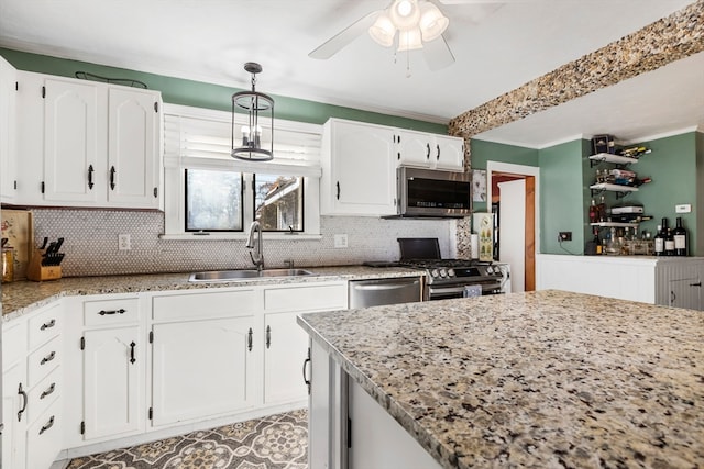 kitchen featuring hanging light fixtures, light stone counters, appliances with stainless steel finishes, white cabinetry, and sink