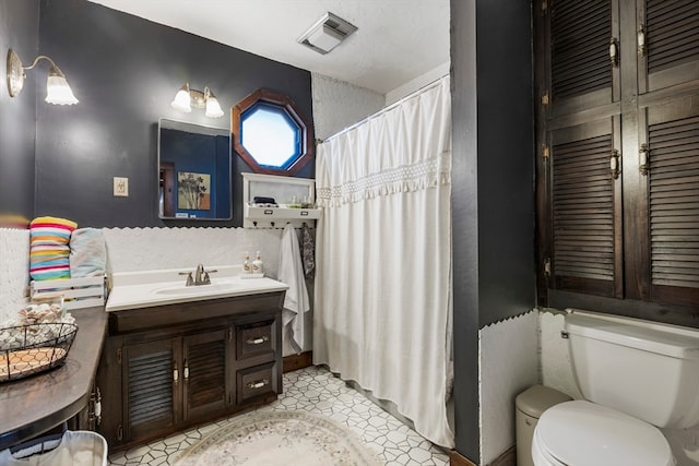 bathroom with toilet, vanity, and tile patterned floors