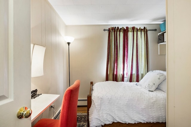 bedroom with wooden walls, a baseboard heating unit, and dark hardwood / wood-style flooring