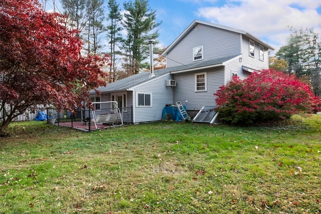 back of house with a wall mounted air conditioner and a yard