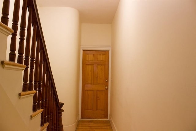 staircase featuring wood finished floors and baseboards
