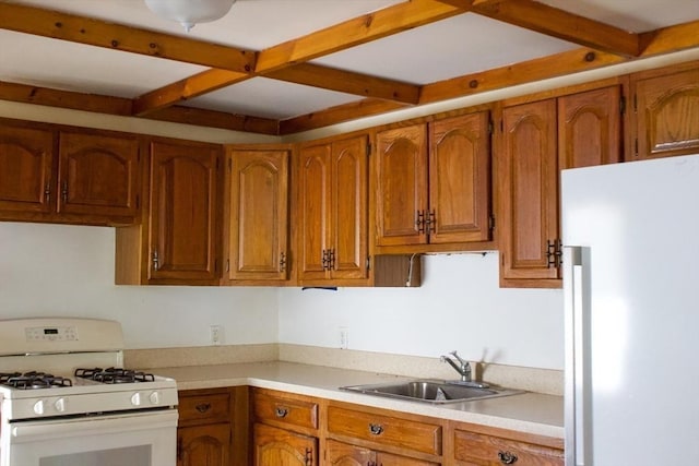 kitchen with white appliances, a sink, beam ceiling, brown cabinets, and light countertops