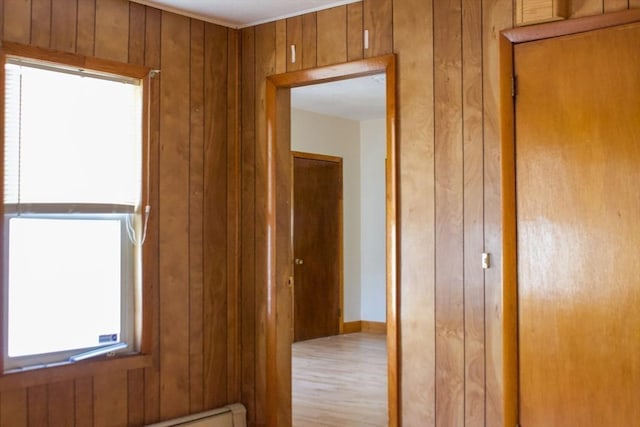 hallway featuring wood walls, wood finished floors, and a baseboard radiator