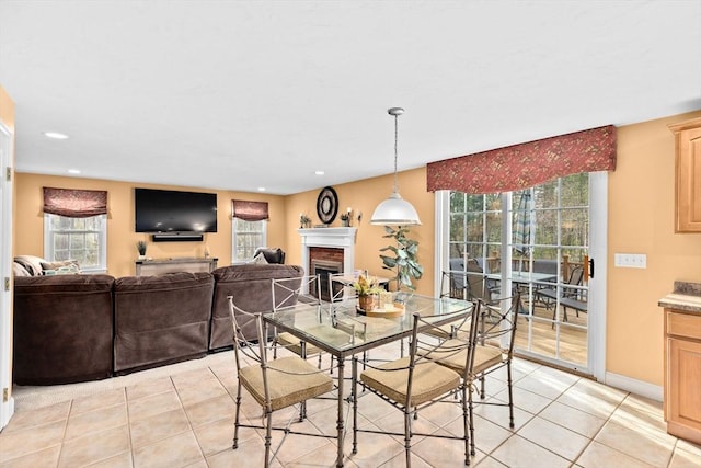 dining area featuring a fireplace, light tile patterned floors, and a healthy amount of sunlight