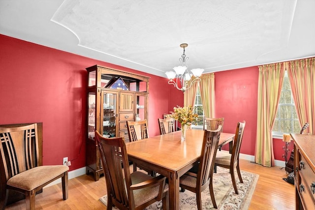 dining space with light hardwood / wood-style floors and an inviting chandelier