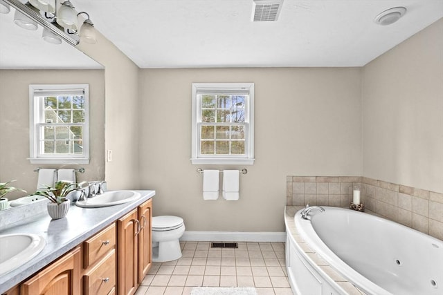 bathroom featuring tile patterned floors, vanity, toilet, and tiled bath