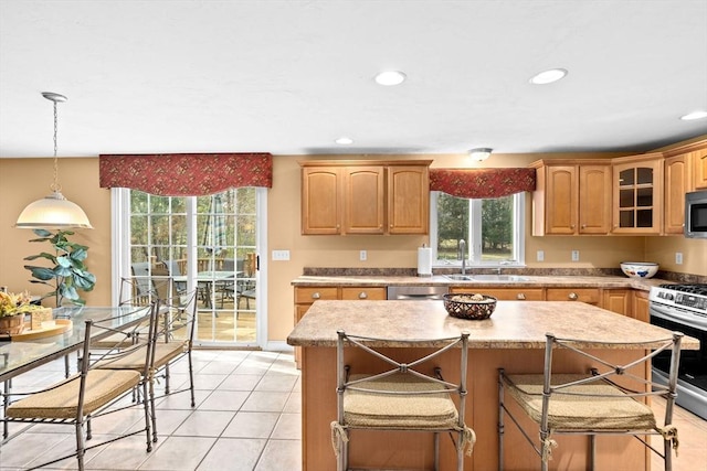 kitchen with a wealth of natural light, sink, light tile patterned floors, and stainless steel appliances