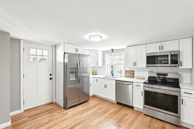 kitchen featuring light countertops, appliances with stainless steel finishes, decorative backsplash, and a sink