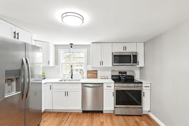 kitchen featuring light countertops, white cabinets, tasteful backsplash, light wood finished floors, and stainless steel appliances