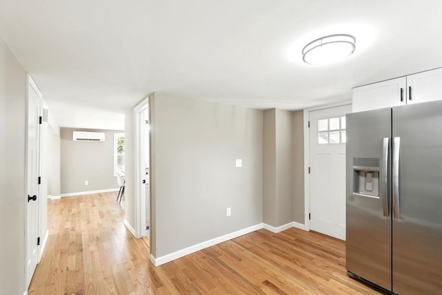 interior space with stainless steel fridge, a wall mounted air conditioner, light wood-style floors, and baseboards