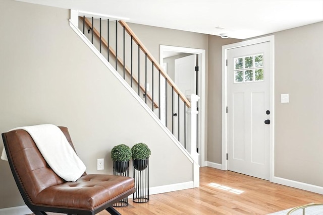 entryway featuring baseboards, wood finished floors, and stairway