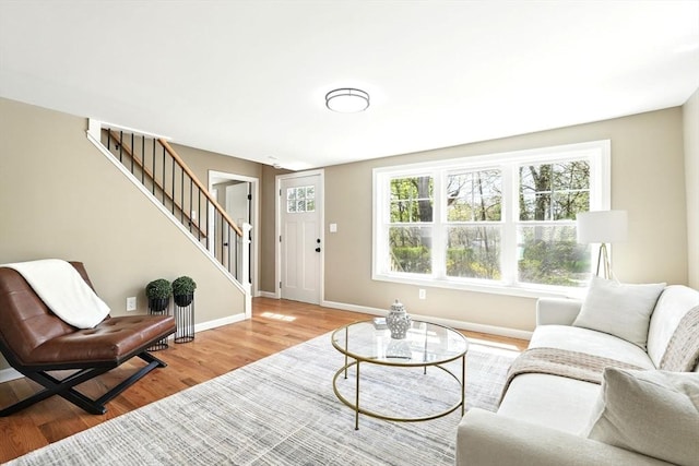 living area with stairway, baseboards, and wood finished floors