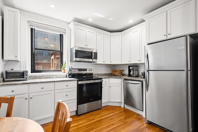 107 Jersey St Unit 16, Boston, MA 02215 - kitchen with a toaster, light wood-style floors, recessed lighting, white cabinets, and stainless steel appliances