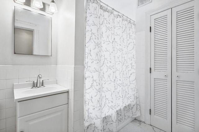 107 Jersey St Unit 16, Boston, MA 02215 - bathroom featuring visible vents, tile walls, wainscoting, vanity, and shower / tub combo with curtain