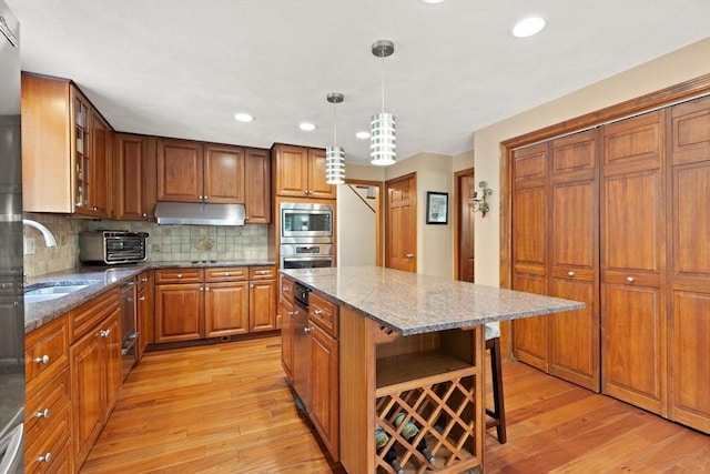 41B Washington St, Boxford, MA 01921 - kitchen featuring stainless steel appliances, light wood-type flooring, brown cabinets, stone countertops, and tasteful backsplash