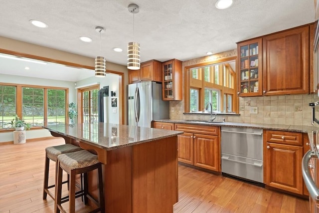 41B Washington St, Boxford, MA 01921 - kitchen with appliances with stainless steel finishes, brown cabinetry, a breakfast bar area, a kitchen island, and tasteful backsplash
