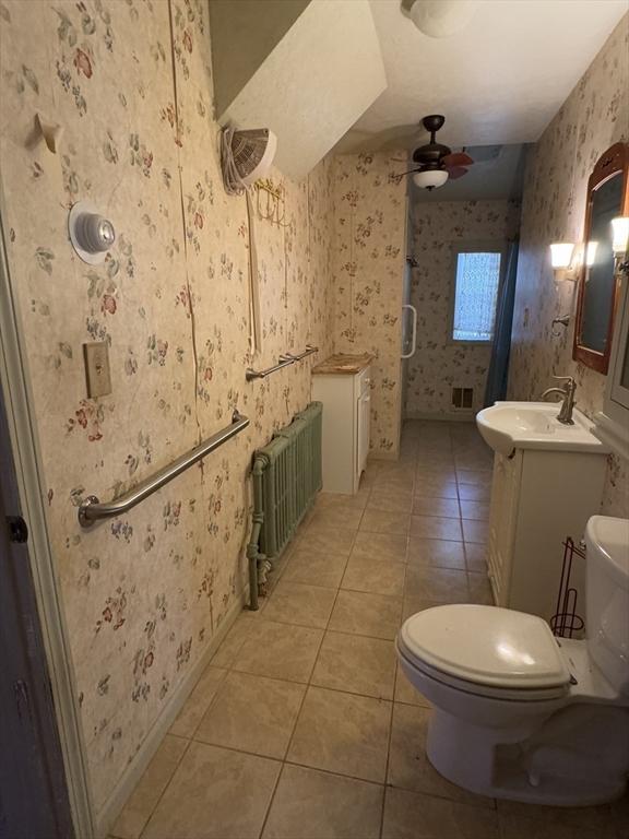 full bathroom featuring toilet, a ceiling fan, tile patterned floors, radiator, and wallpapered walls