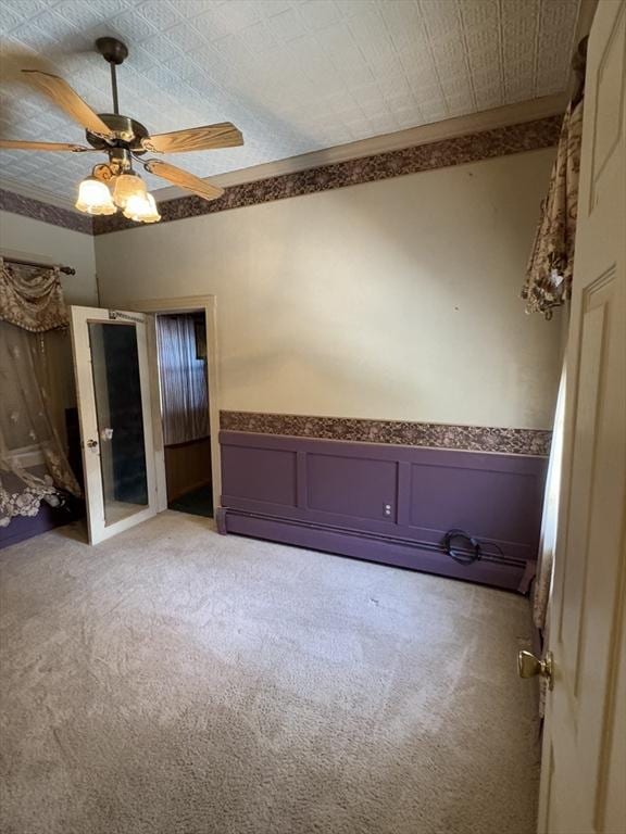 unfurnished bedroom with wainscoting, light carpet, and ceiling fan