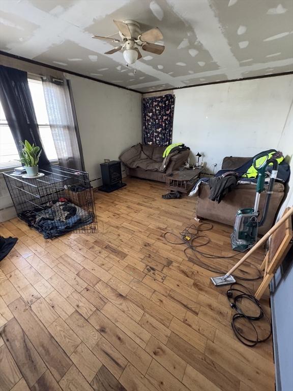 living area featuring ceiling fan, baseboard heating, and wood finished floors