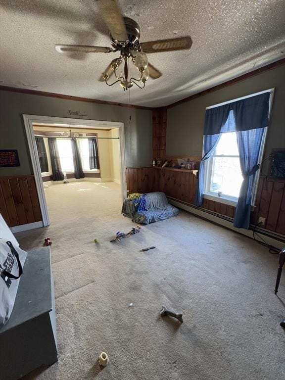 unfurnished bedroom featuring a textured ceiling, a ceiling fan, baseboard heating, and carpet flooring