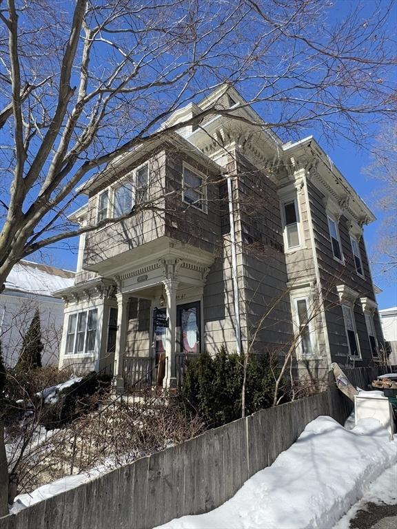 italianate home featuring a fenced front yard and a balcony