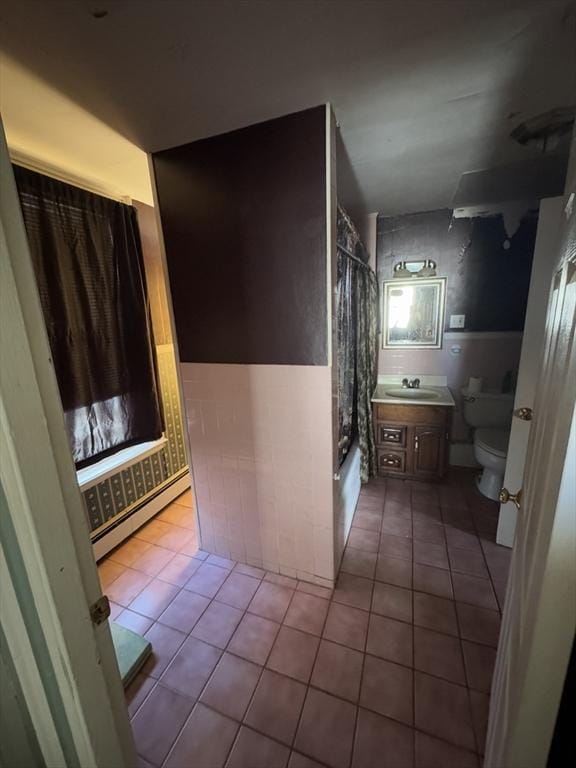 bathroom with toilet, shower / bathtub combination with curtain, a baseboard heating unit, and tile patterned floors