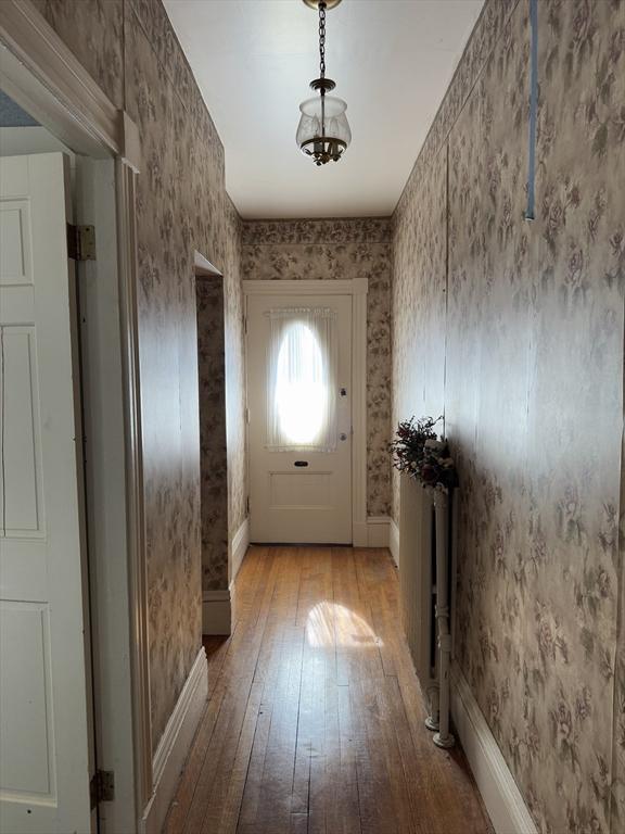 entryway featuring hardwood / wood-style flooring, baseboards, and wallpapered walls