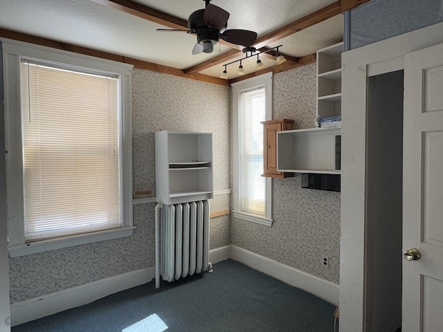 unfurnished room with dark colored carpet, baseboards, radiator heating unit, and wallpapered walls