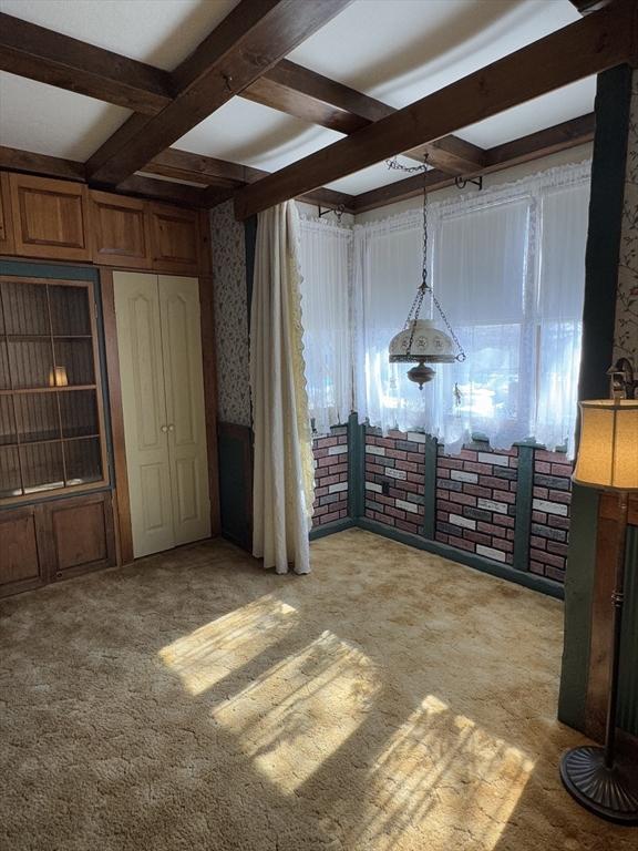 unfurnished bedroom featuring light carpet, wallpapered walls, coffered ceiling, and beam ceiling