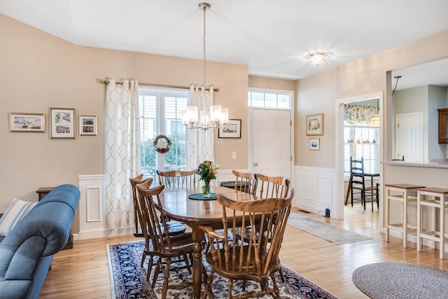 dining area with light hardwood / wood-style flooring and a notable chandelier