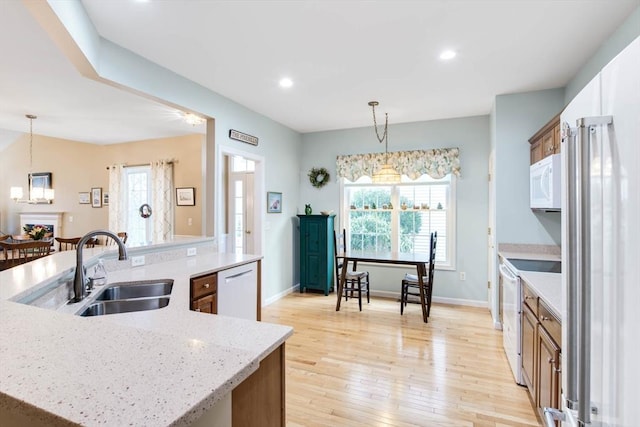 kitchen featuring light stone countertops, sink, decorative light fixtures, and white appliances