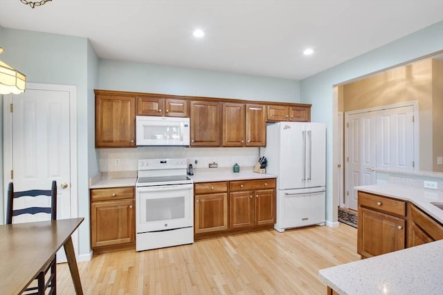 kitchen featuring white appliances, backsplash, and light hardwood / wood-style flooring