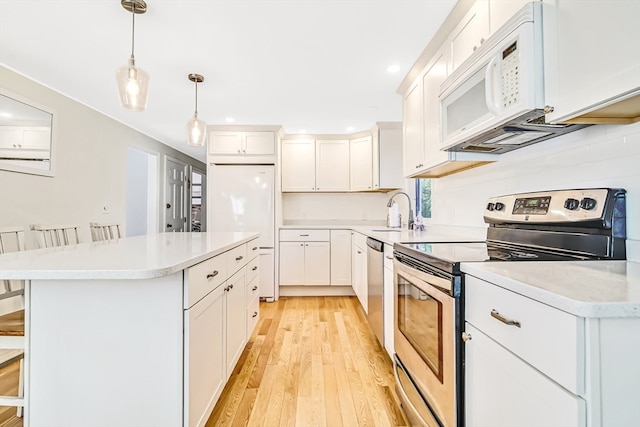 kitchen with light wood-type flooring, white cabinetry, appliances with stainless steel finishes, and decorative light fixtures