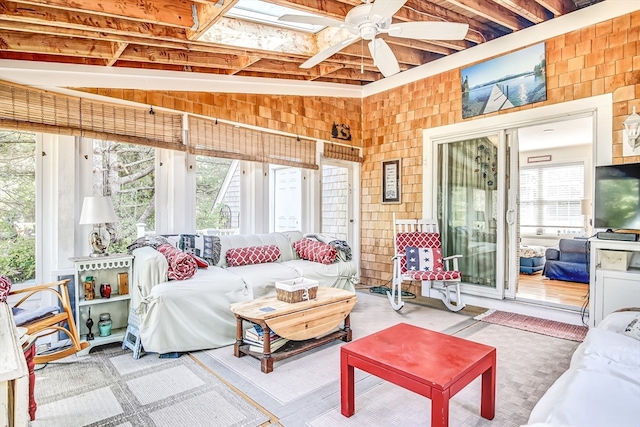 sunroom featuring ceiling fan, vaulted ceiling with skylight, and plenty of natural light