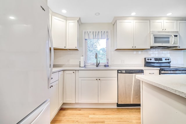 kitchen with light hardwood / wood-style flooring, white cabinetry, appliances with stainless steel finishes, and sink